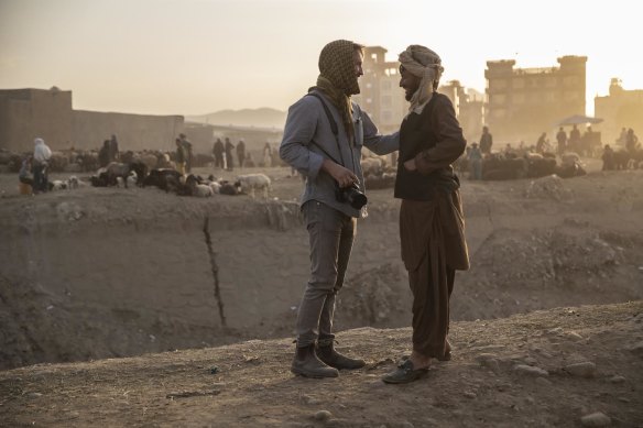 Quilty speaks with a local at a Kabul market on the morning of Eid.