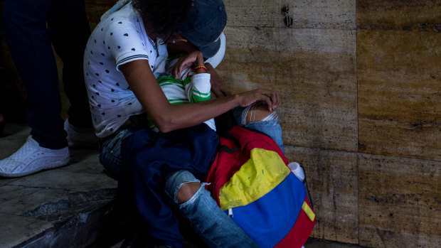 A woman cradles her chronically sick child at a demonstration protesting health cuts outside  Venezuela's Health Ministry last week.