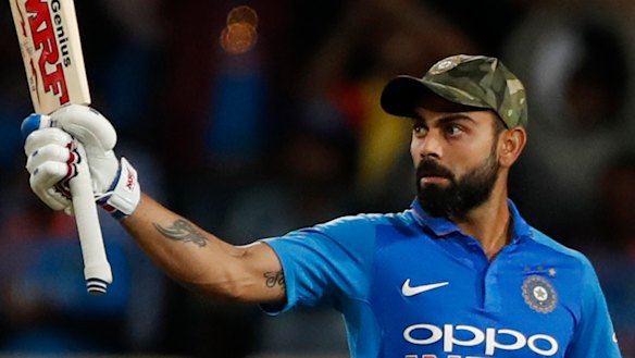 Captain Virat Kohli raises his bat to celebrate scoring a century.