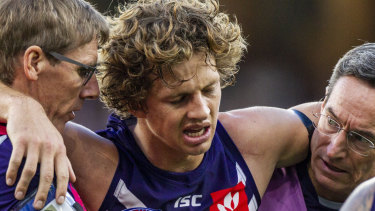 Out of action: Fremantle caption Nat Fyfe is escorted off the ground after a clash of heads, and didn't return to the game.