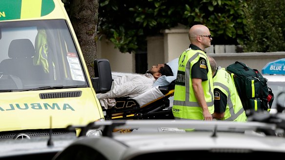 Ambulance staff take a man from outside a mosque in central Christchurch following a mass shooting.