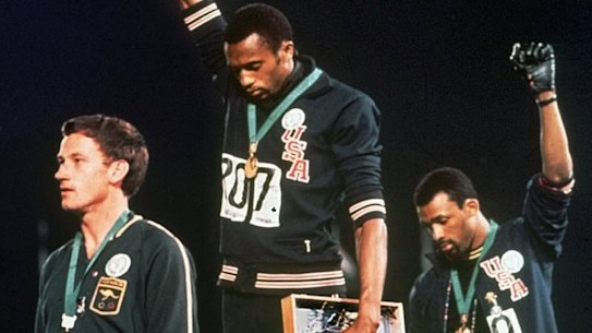 US athletes Tommie Smith, center, and John Carlos stare downward during the playing of national anthem after Smith received the gold and Carlos the bronze for the 200-metre sprint at the 1968 Olympic Games in Mexico City. Australian silver medalist Peter Norman is at left.
