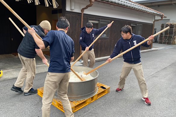 Matt Froude, wearing a beret, threshes rice with his co-workers at the Matsuse sake brewery in Japan's Shiga prefecture.