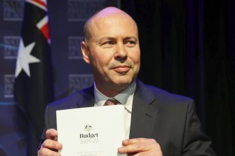 Treasurer Josh Frydenberg poses for photos with budget papers before delivering his post-budget address to the National Press Club.