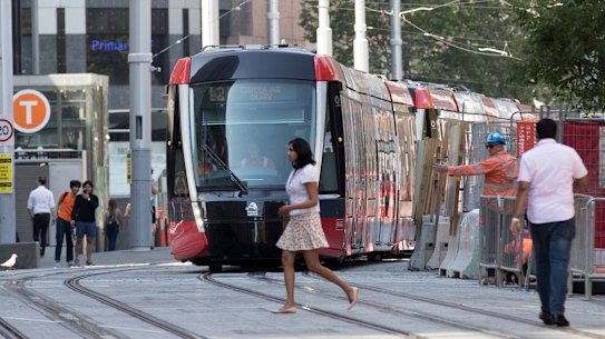 A pedestrian crosses in front of a tram.