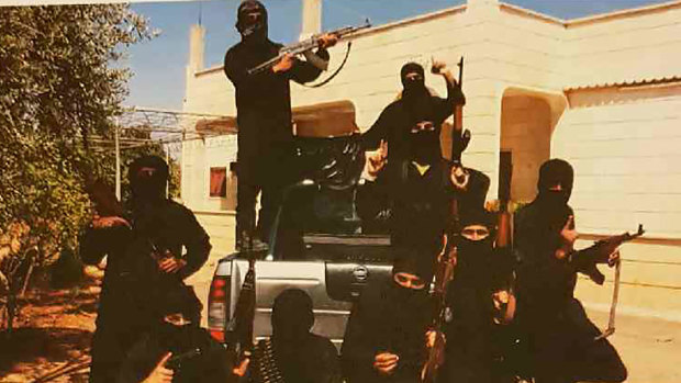 Mehmet Biber poses with insurgents in Syria. He is pictured inside the tray of the vehicle wearing a white watch.