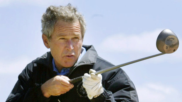George W.  Bush points a golf club at a reporter while refusing to answer a question during his presidency.