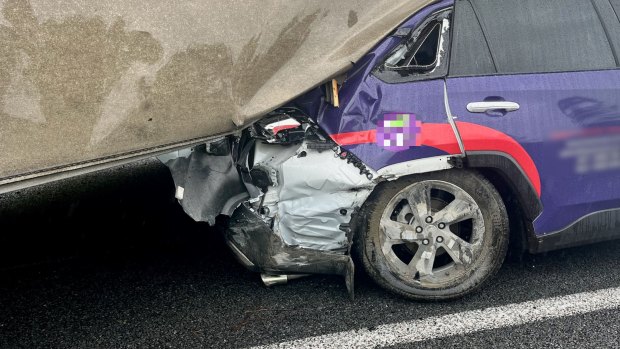 A truck has rolled on the Pacific Motorway south of Brisbane, its trailer crushing a car.