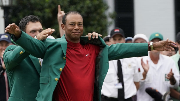 Last year's Masters winner Patrick Reed helps Tiger Woods put on the famous green jacket.