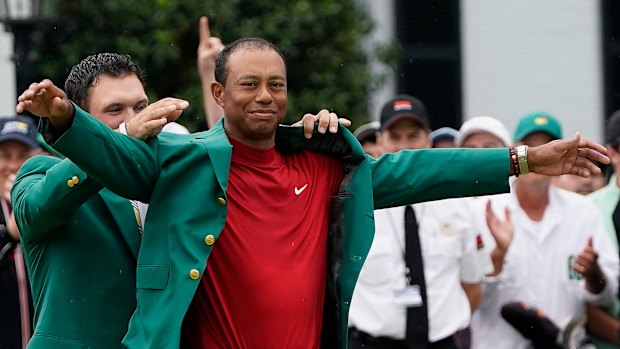 Last year's Masters winner Patrick Reed helps Tiger Woods put on the famous green jacket.