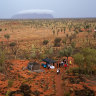 Uluru in the distance covered by cloud as guests gather for Field of Light.