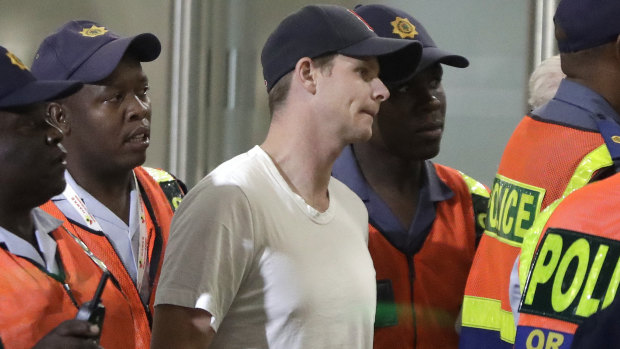 Heading home: Steve Smith with a police escort at Tambo International airport in Johannesburg.