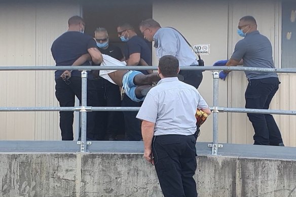 Officials carry one of the men into a room at the Brisbane Immigration Transit Accommodation site.