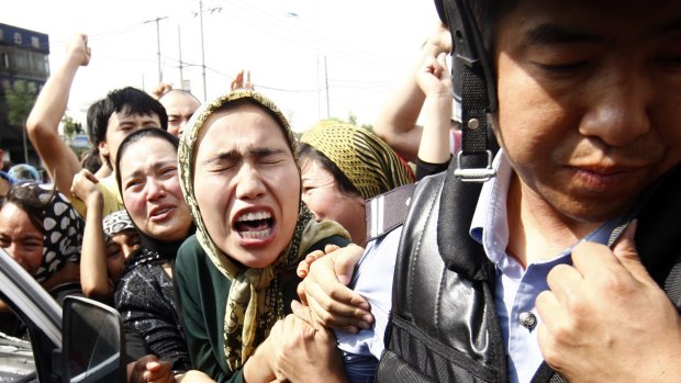 An angry crowd belonging to the Chinese Uyghur Muslim minority try to grab hold of a police officer during protests in Urumqi, China, in 2009. 