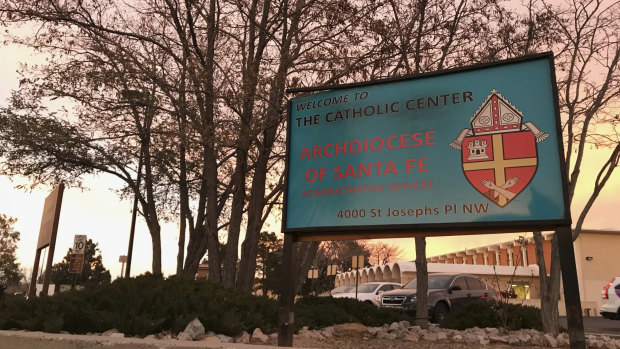 The sun sets on a sign in front of the Archdiocese of Santa Fe offices in Albuquerque. The archdiocese is in bankruptcy proceedings as a result of the abuse scandal involving 70 clergy members.