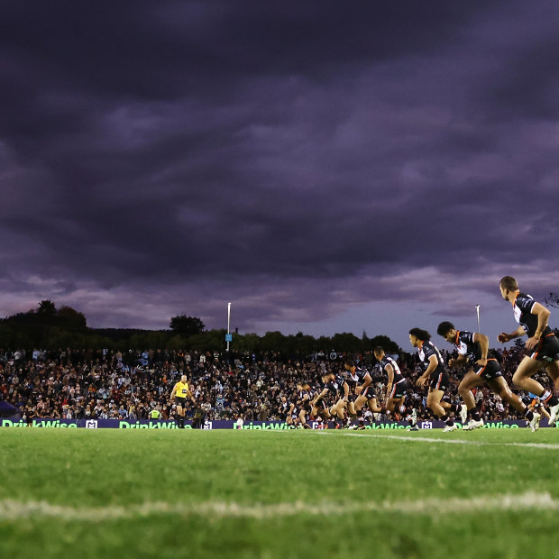 Dark clouds over bush footy ... The Tigers kick off during the round 22 NRL match against the Sharks at Scully Park, Tamworth.