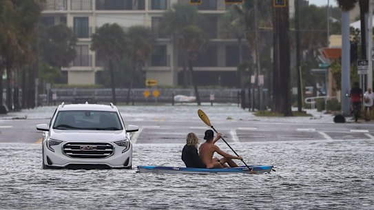 People kayak past an abandon vehicle in the intersection of Boca Ciega Drive and Pasadena Avenue 