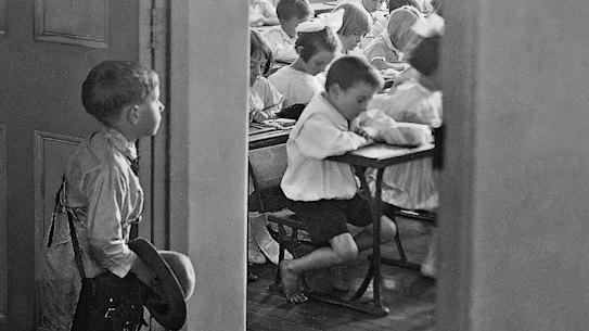 A young boy stares into a classroom full of students on his first day of school.