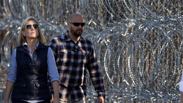 Secretary of Homeland Security Kirstjen Nielsen, left, walks next to a section of the border wall fortified with razor wire separating Tijuana, Mexico, and San Diego, on Tuesday.