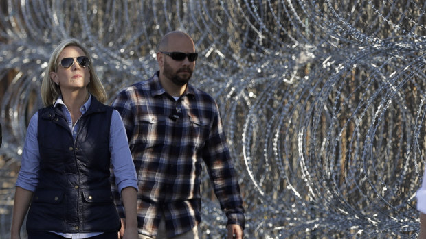 Secretary of Homeland Security Kirstjen Nielsen, left, walks next to a section of the border wall fortified with razor wire separating Tijuana, Mexico, and San Diego, on Tuesday.
