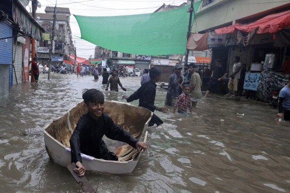 A boy uses half of a fiber tank to navigate a flooded street after heavy monsoon rains, in Karachi, Pakistan, in August.