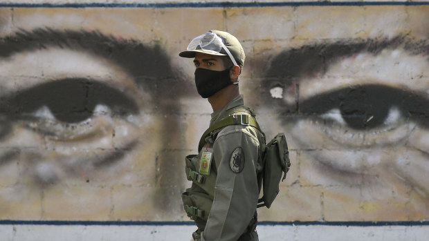 A soldier guards a voting poll at a school that has the eyes of the late President Hugo Chavez painted on a wall during elections to choose members of the National Assembly in Caracas.