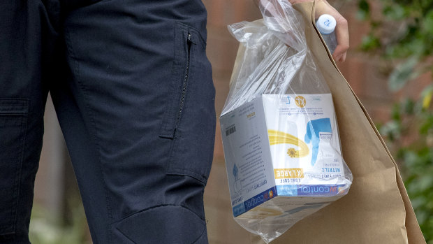 Federal police leave the house of one of the terror suspects with a packet of rubber gloves.