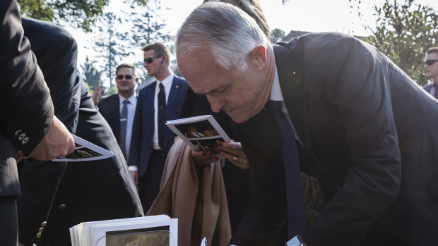 Malcolm Turnbull and his wife, Lucy, sign the condolence book outside the memorial service for Sir John Carrick.