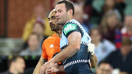 Boyd Cordner is helped from the field by Roosters and Blues trainer Travis Touma.