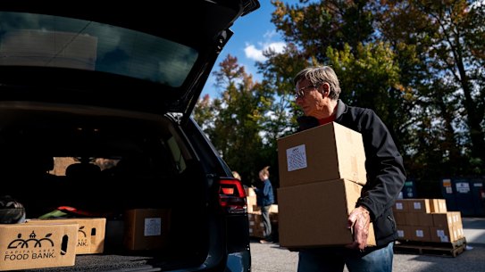 A volunteer loads a box of food into the car of a furloughed federal worker at a Capital Area Food Bank in Virginia.