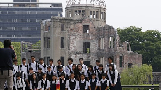 School children pose for a group photo with the Atomic Bomb Dome as a backdrop in the Hiroshima Peace Memorial Park.