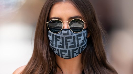 A woman wears a mask printed with the Fendi logo.