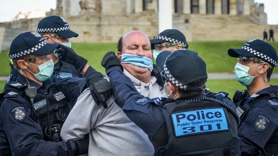 Police arrest a man and try to put a mask on him. He was the first of dozens to be marched away.