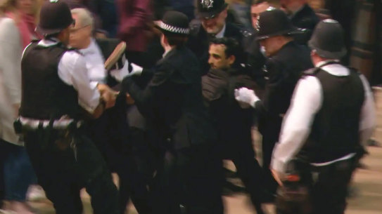 A screen grab of police at Westminster Hall wrestling a man to the ground after he rushed towards the Queen’s coffin and tried to pull at the flag draped over it. 
