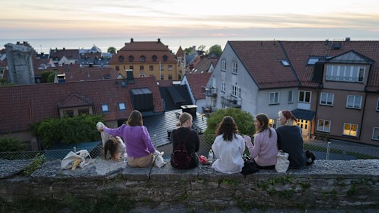 Limited to groups of eight: people sit along a street in the town of Visby in Gotland, Sweden. 