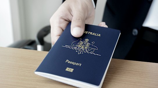 Hands giving passport (of Australia) - dark tone iStock image for Traveller. Re-use permitted. Australian passport generic Australia