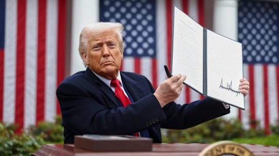 US President Donald Trump displays the signed executive order after his tariff announcement.