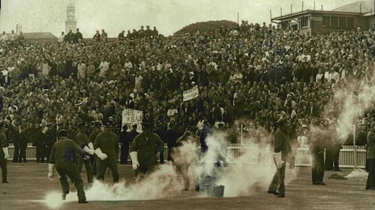 Police pick up missiles and smoke bombs hurled by demonstrators from the hill at SCG during the NSW- Springboks rugby match to day. July 10, 1971.