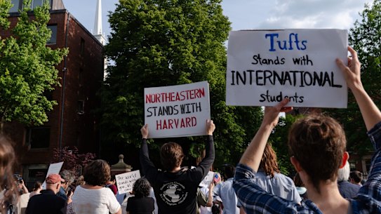 Demonstrators hold signs during a protest in support of international students at Harvard University.
