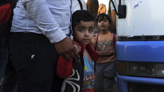 A Syrian boy holds his father's hand after disembarking from one of the buses that brought 784 Syrian refugees to Bardarash Refugee Camp in Iraqi Kurdistan.
