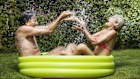 Mature couple splashing in paddlingpool.