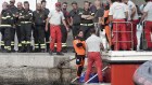 Rescue divers arrive back with a fifth body from the luxury yacht.