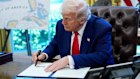US President Donald Trump signs an executive order in the Oval Office.