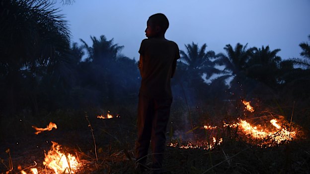 Former child soldier Wilson, 15 years old, watches over a small fire in his village in Kasai Central.