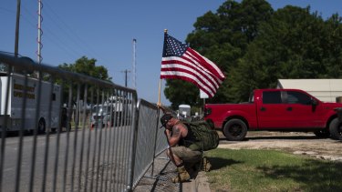 Jarrod Tomassi, 45, holds an American flag outside Robb Elementary School while praying for the victims killed in this week's school shooting in Uvalde, Texas, Saturday, May 28, 2022. (AP Photo/Jae C. Hong)