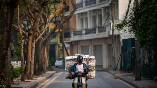 HANOI, VIETNAM - A delivery man with toilet paper rides past the quarantined area of Truc Bach Street wearing facemask amid concerns of the spread of the COVID-19 coronavirus on March 9, 2020 in Hanoi, Vietnam. 