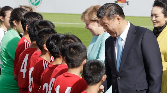 Then-German chancellor Angela Merkel and Chinese President Xi Jinping greet players before a match between the U12 teams of Germany and China in Berlin, in 2017.
