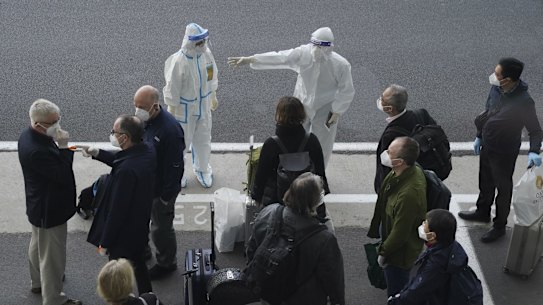 A worker in protective gear directs members of the World Health Organisation (WHO) team in Wuhan earlier this year. 