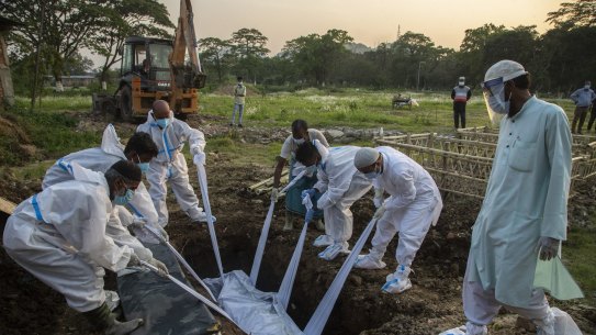 Relatives and municipal workers in protective suit bury the body of a COVID-19 victim.