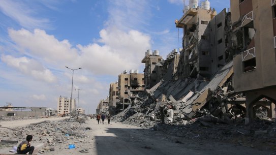 Palestinians pass the remains of buildings following the withdrawal of the Israeli military from Hamad City, west of Khan Younis, Gaza.